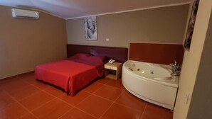 A small hotel room with a bed, a nightstand, a telephone, and a bathtub. - Miga Hotel Airport (Isola di Capo Rizzuto)