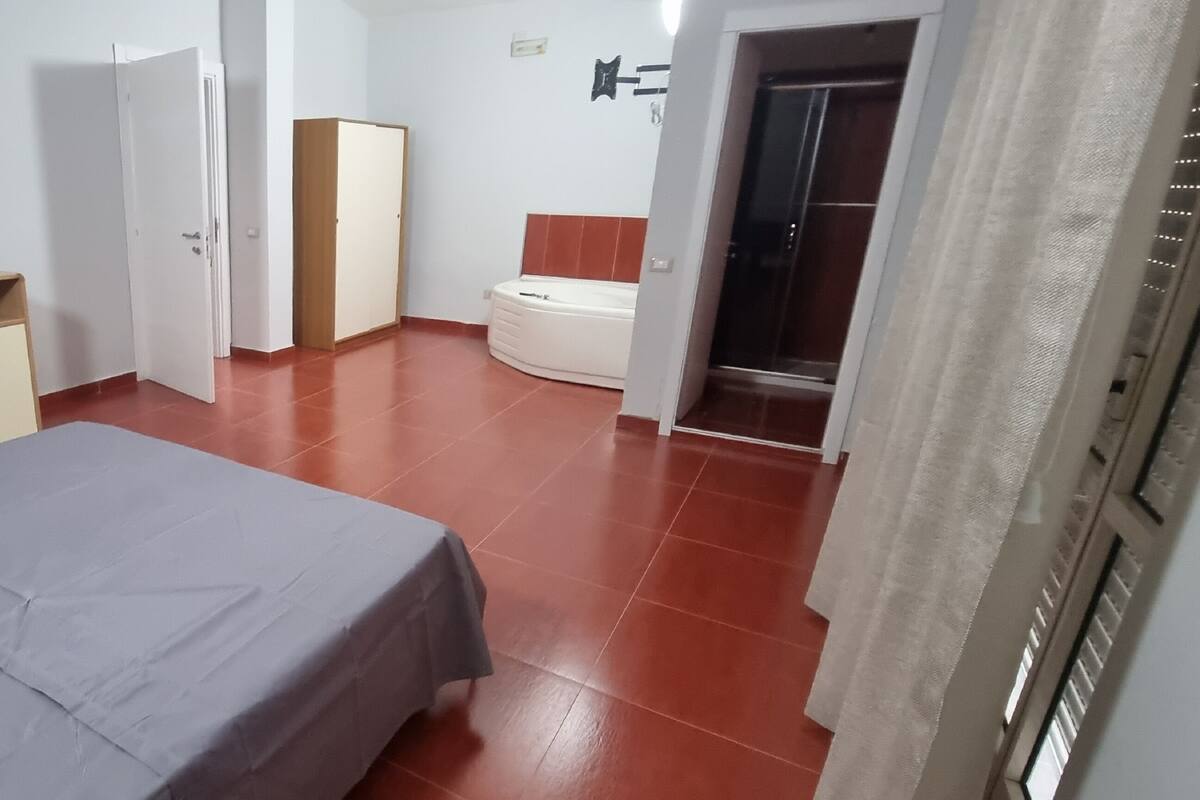 A bedroom with a bed, a desk, a wardrobe, and a bathroom.