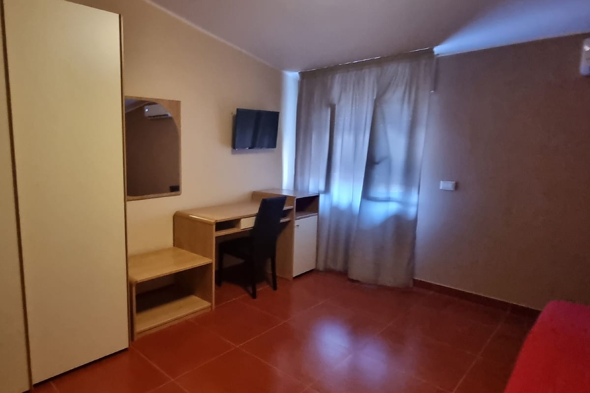 A compact room with a desk, chair, and a television mounted on the wall.