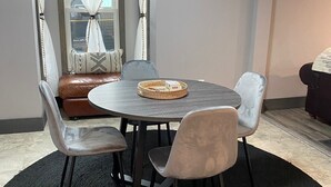 A dining area with a round table, four chairs, a woven basket, and a bench with a cushion. - Colorful Cape Cod (Lexington)