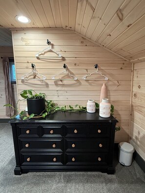 A black dresser with drawers, a potted plant, and decorative items on top.