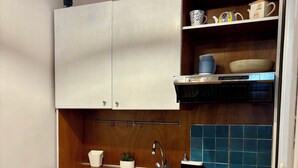 Una cocina compacta con gabinetes blancos, un lavamanos de acero inoxidable y un lavavajillas pequeño.