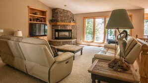 A living room with a stone fireplace, leather sofa, and a lamp. - Shady Crest. Pool table, fireplace, games, kayaks, Legos. 5 kings - 16ppl. (Brainerd)