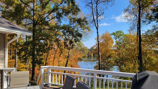 A deck with outdoor seating and a view of a lake surrounded by trees. - Shady Crest. Pool table, fireplace, games, kayaks, Legos. 5 kings - 16ppl. (Brainerd)