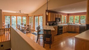 A spacious kitchen with wooden cabinets, a central island, and large windows. - Shady Crest. Pool table, fireplace, games, kayaks, Legos. 5 kings - 16ppl. (Brainerd)