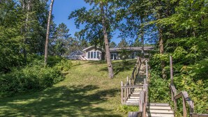 A wooden staircase leading to a house surrounded by lush greenery. - Shady Crest. Pool table, fireplace, games, kayaks, Legos. 5 kings - 16ppl. (Brainerd)