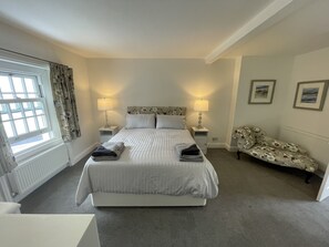 A neatly arranged bedroom with a large bed, two bedside tables with lamps, a sofa, and a window with curtains. - Stunning Three Bedroom House in West Runton (Cromer)