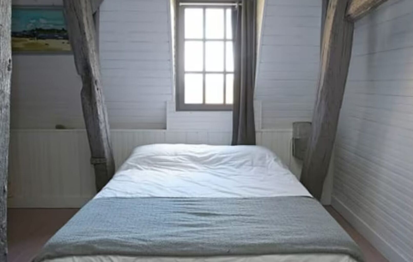 A narrow room with a single bed, a window, and a radiator.