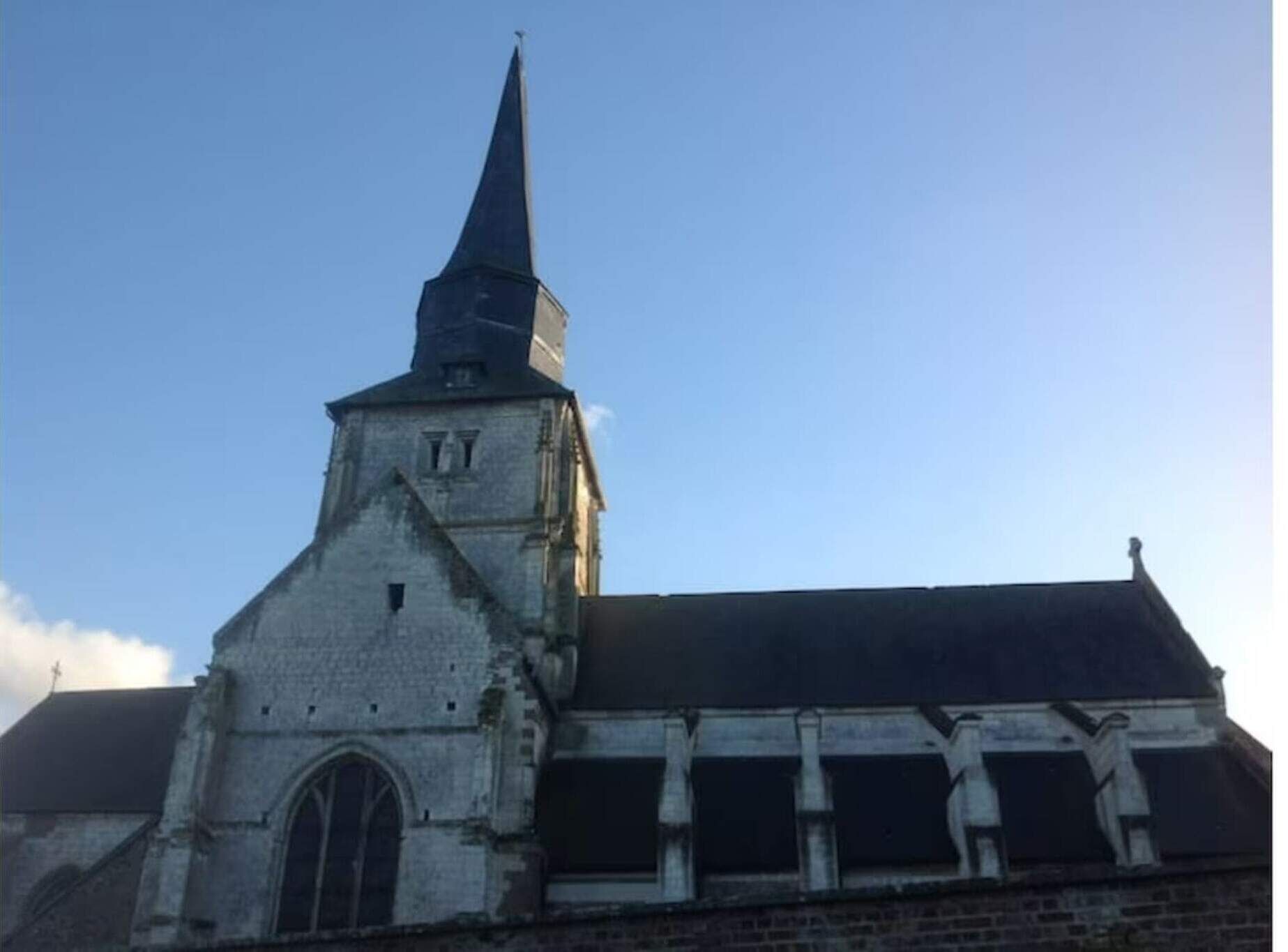 Een kerk met een hoge spits en een brede, gebogen ingang.