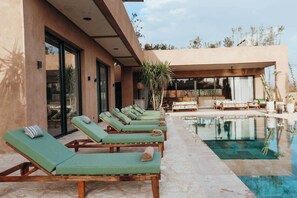 A poolside area with lounge chairs, a pool, and a covered seating area.