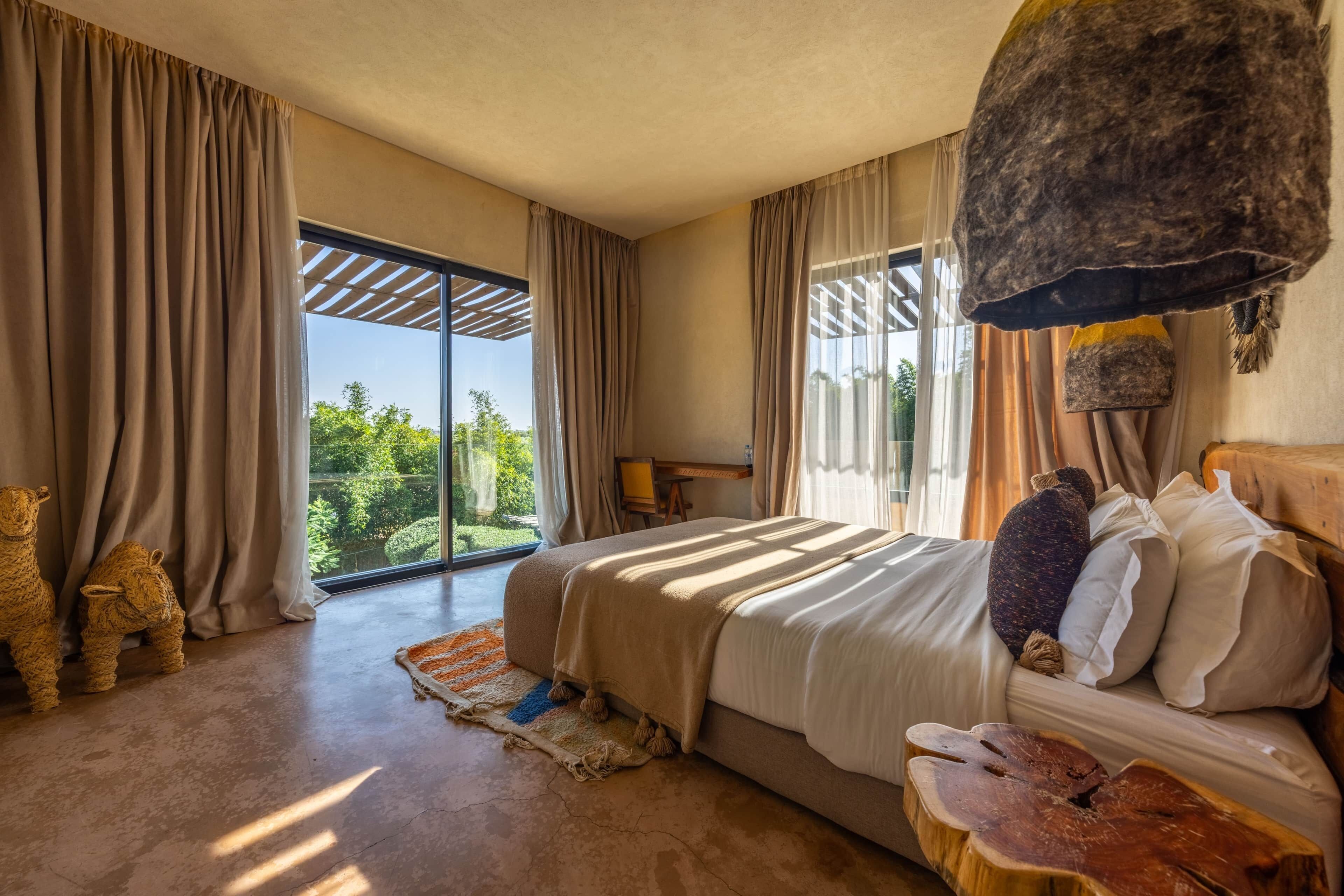 Ein Schlafzimmer mit einem großen Bett, Blick auf Grünflächen und rustikalem Dekor.