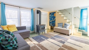 A living room with a sofa, a couch, a rug, a fireplace, and a staircase. - Hudson Valley Apartment in a Historic Farmhouse w/ Sauna Near Stone Ridge Hamlet (Stone Ridge)