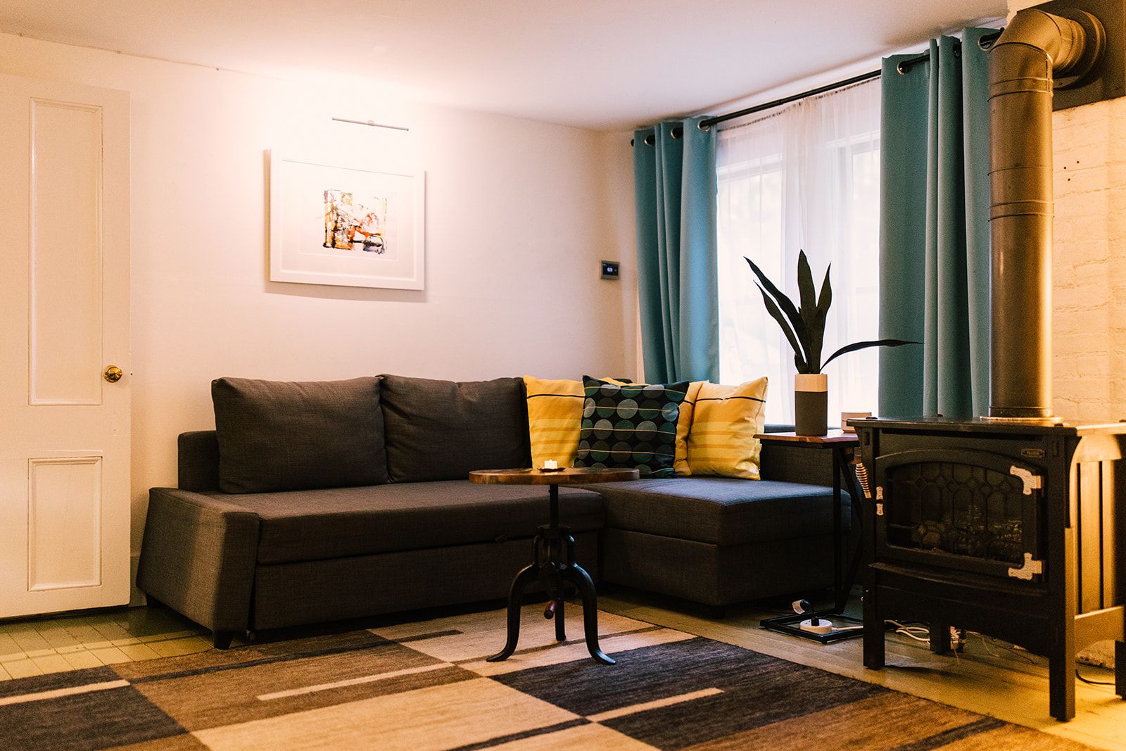 A living room with a sofa, a small table, a fireplace, and a window with curtains.