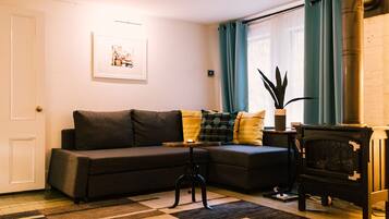 A living room with a sofa, a small table, a fireplace, and a window with curtains.
