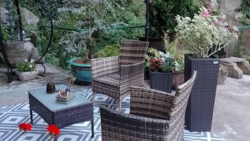 An outdoor seating area with wicker furniture, a patterned rug, and potted plants.