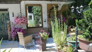 Un patio con plantas en macetas, una silla de mimbre y un banco.
