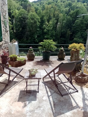Une terrasse avec deux chaises, une table et des plantes en pot.