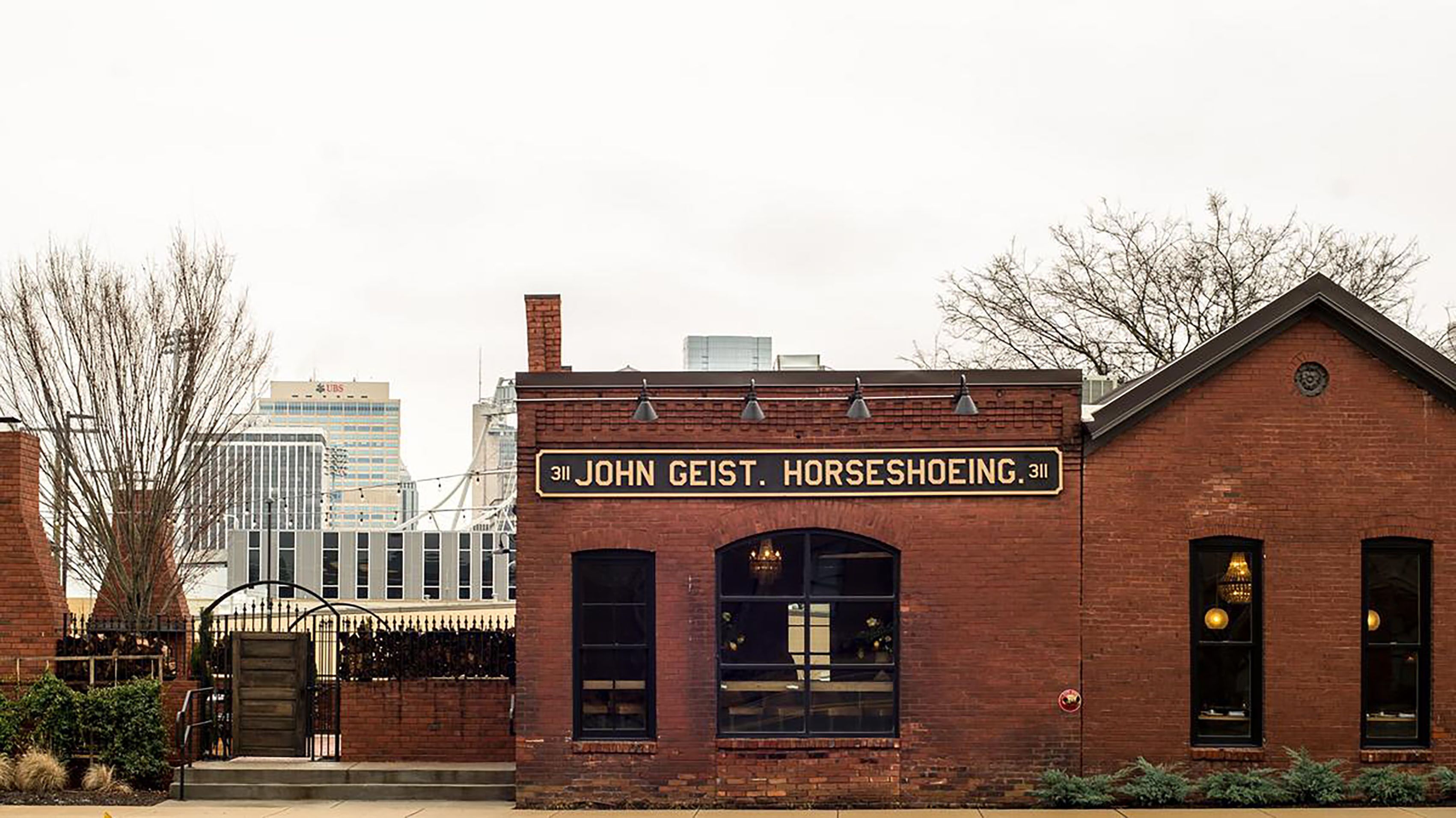 A brick building with a sign reading "John Geist. Horseshoeing."