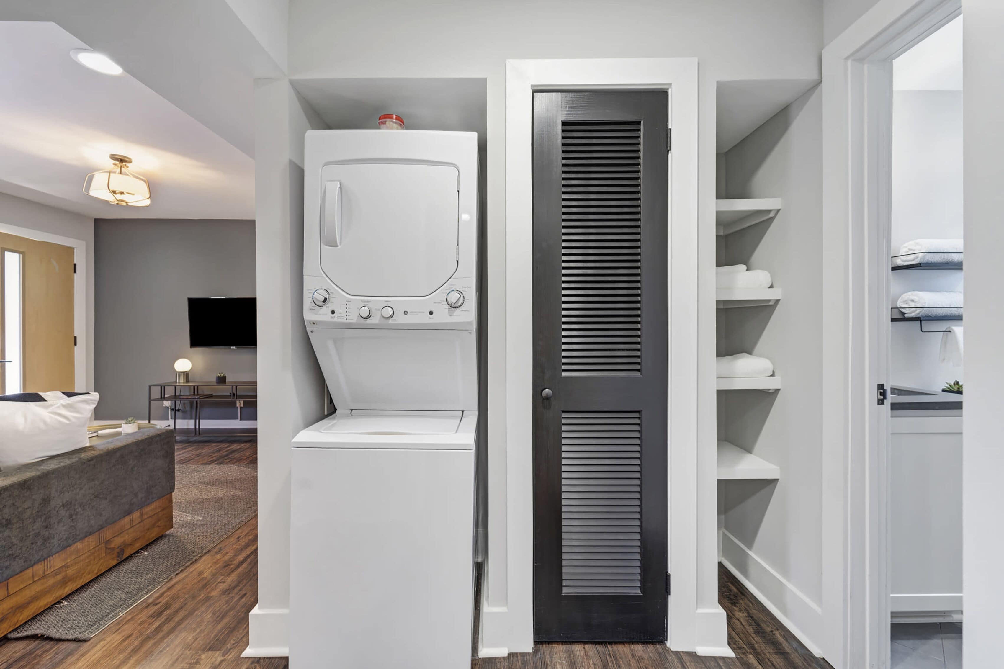A modern bedroom with a bed, a TV, and a built-in washer and dryer.