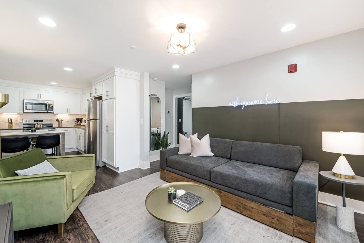 A modern living room with a grey sofa, a green armchair, and a round coffee table.