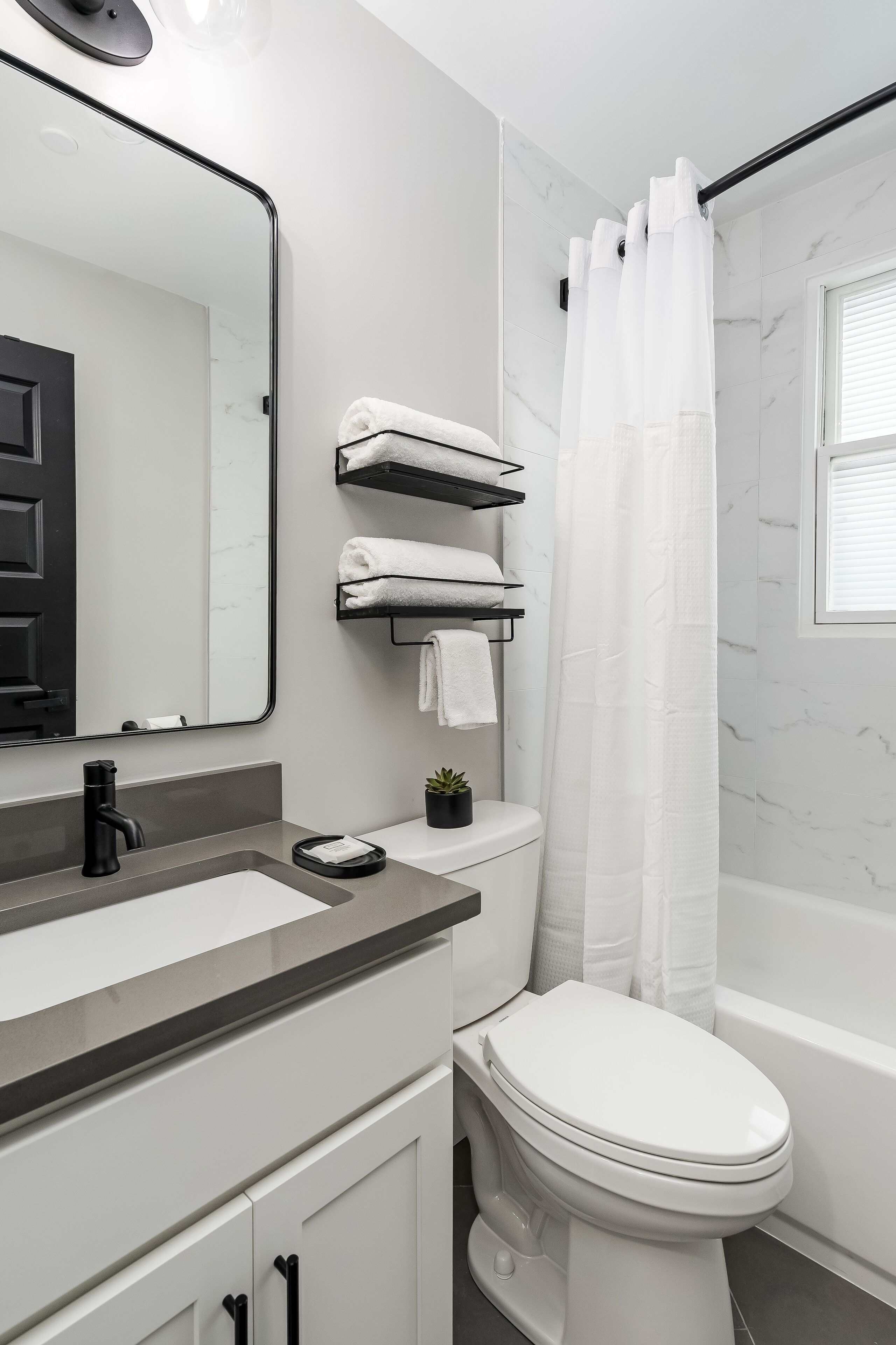 Ein modernes Badezimmer mit Toilette, Waschbecken mit Spiegel und Duschvorhang.