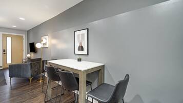 A modern dining area with a wooden table, black chairs, and a grey wall.