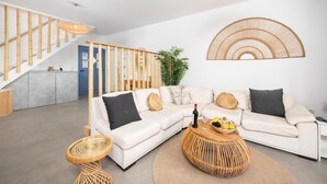 Una sala de estar moderna con un sofá blanco, una mesa de centro y una escalera con barandillas de bambú.
