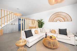 Un salon moderne avec un canapé blanc, une table basse et un escalier doté de rampes en bambou.