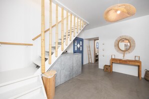 A modern interior with a staircase, a console table with a mirror, and a hanging light fixture.