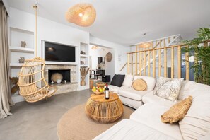 A modern living room with a sofa, a television, a fireplace, and a staircase with bamboo railings. - Villa Canova - Three Bedroom Villa, Sleeps 6 (Ionian Islands)