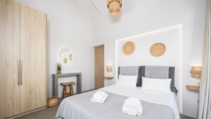 Un dormitorio moderno con una cama grande, un armario de madera, un taburete pequeño y un espejo en la pared.