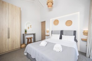 Une chambre à coucher moderne avec un grand lit, une armoire en bois, un petit tabouret et un miroir au mur.