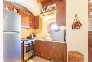 Una cocina compacta con armarios de madera, un refrigerador de acero inoxidable, una estufa y un lavamanos.