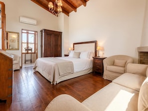 Un dormitorio con una cama grande, un armario de madera y una silla.