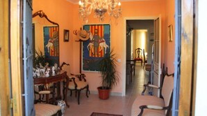 Un couloir agrémenté d’un lustre, un coin repas avec des chaises et une table, et un tableau coloré accroché au mur.