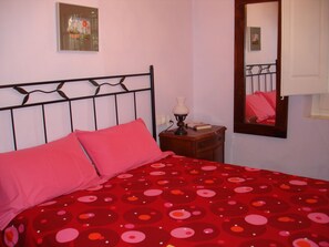 Ein Schlafzimmer mit Bett, Nachttisch, Lampe und Spiegel.