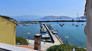 A marina with boats docked, a pier extending into the water, and mountains in the background. - Holiday home near the sea (Baška)