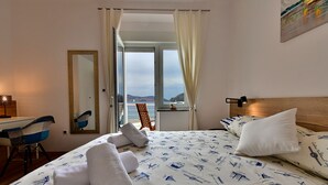 Une chambre d’hôtel avec un lit, un bureau, une chaise et une vue sur la mer.