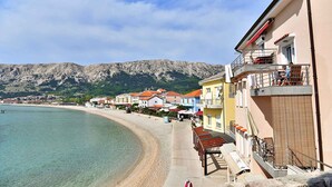 Un bâtiment situé sur la côte, doté de balcons donnant sur une plage et des montagnes.