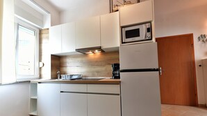 Une cuisine moderne avec des meubles blancs, un four à micro-ondes, une machine à café et un plan de travail en bois.