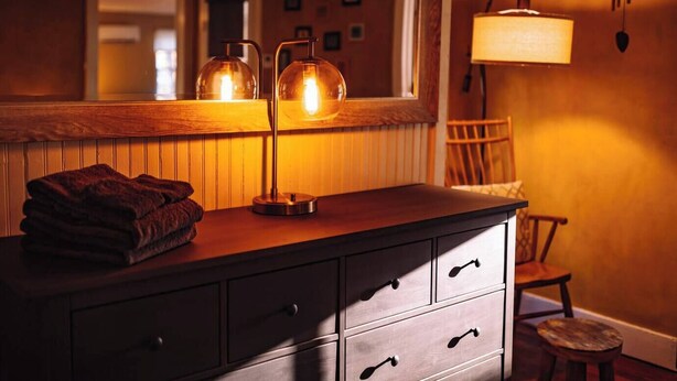 A wooden vanity with a mirror, two pendant lights, and a folded towel. - Historic Hudson Valley Farmhouse Loft in Stone Ridge Hamlet (Stone Ridge)