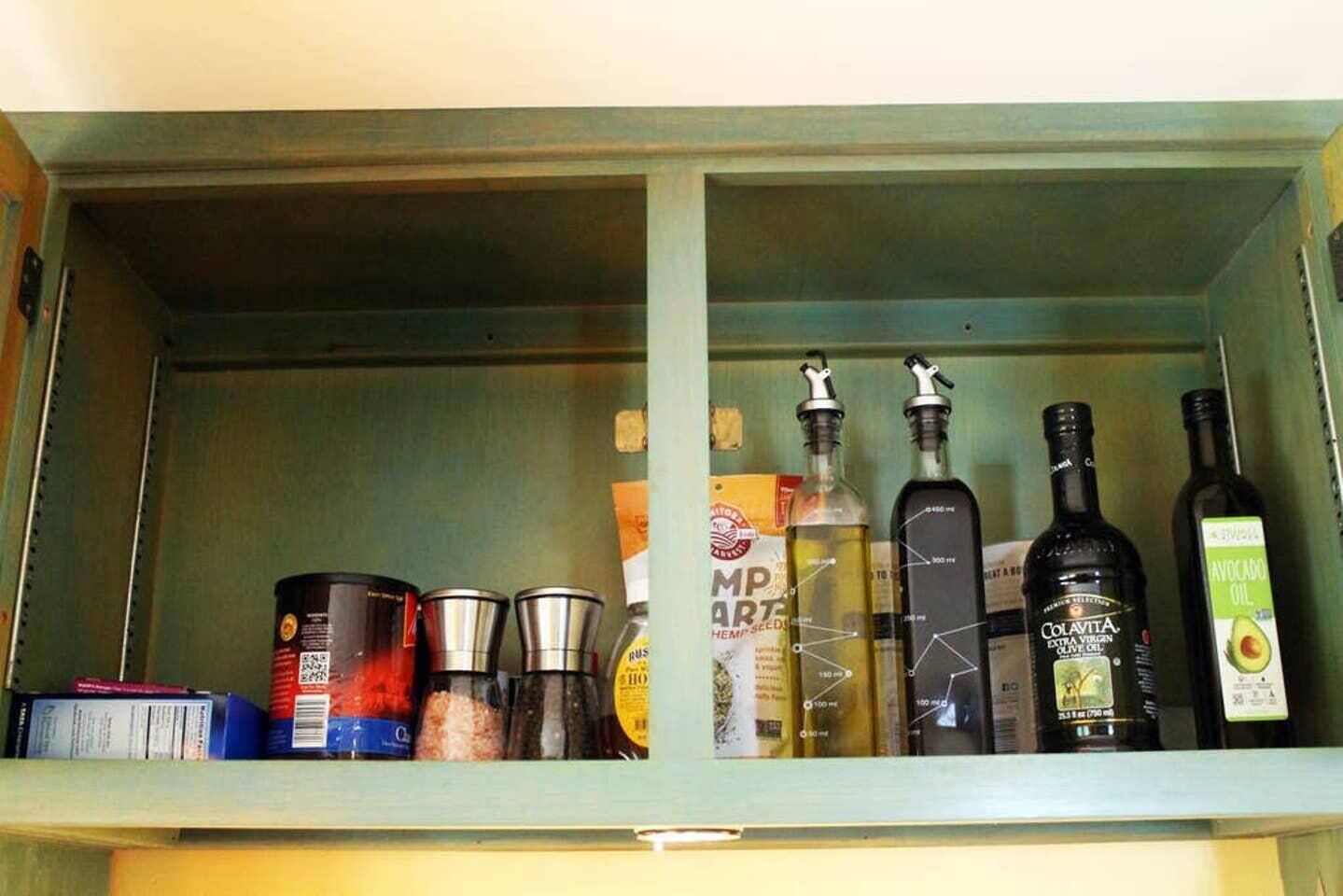 A kitchen cabinet with various food items and bottles.