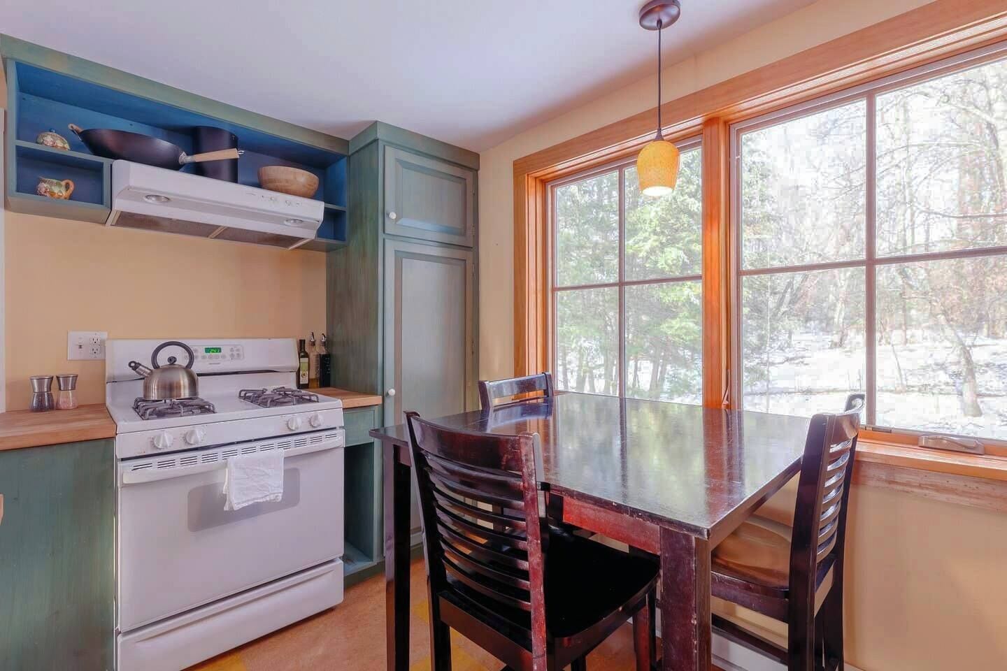 Une cuisine équipée d’une cuisinière, de placards et d’une table à manger avec des chaises.