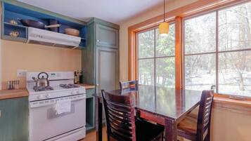Une cuisine équipée d’une cuisinière, de placards et d’une table à manger avec des chaises.
