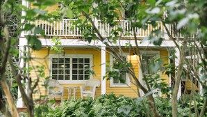 A yellow building with a balcony, surrounded by lush greenery. - Historic Hudson Valley Farmhouse Loft in Stone Ridge Hamlet (Stone Ridge)