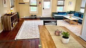 A living room with a wooden coffee table, a sofa, a rug, and a bookshelf. - Historic Hudson Valley Farmhouse Loft in Stone Ridge Hamlet (Stone Ridge)