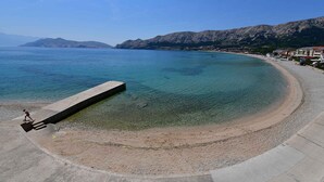 Une zone côtière offrant une vue dégagée sur la mer, avec une promenade en béton et des bâtiments en arrière-plan.