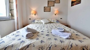 Una camera d'albergo con un letto, due lampade a parete, un quadro e una finestra.