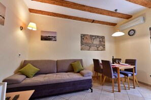 Un salon avec un canapé, une table à manger, des chaises et une horloge au mur.