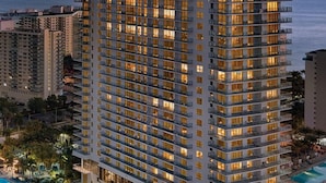 Een hoog hotel met meerdere verdiepingen, balkons en een zwembad.